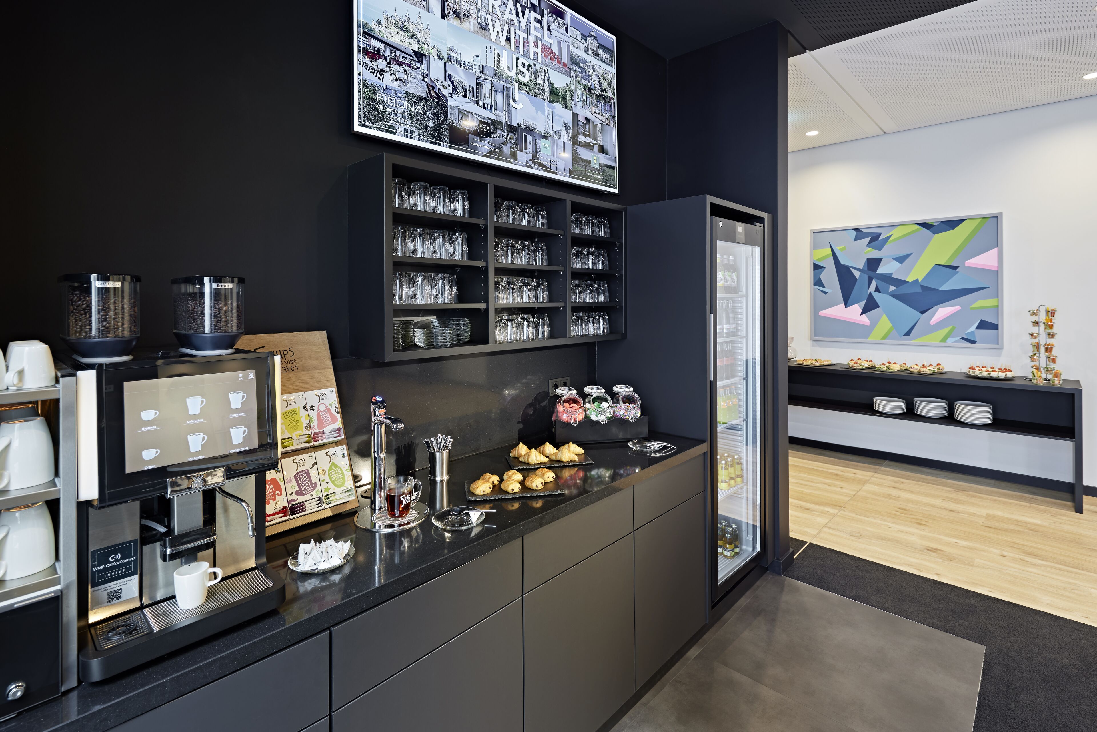 Eine moderne Kaffeestation mit Kaffeemaschine, Tassen und Gebäck.