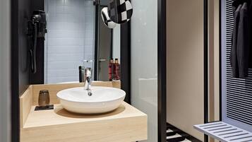 Un baño moderno con un espejo grande, un lavabo redondo y un perchero para toallas.