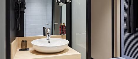 A modern bathroom with a large mirror, a round sink, and a towel rack.