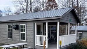 En lille, etetages bygning med veranda, picnicbord og postkasse.