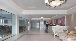 Um saguão de hotel com balcão de recepção, área de estar e parede de vidro.