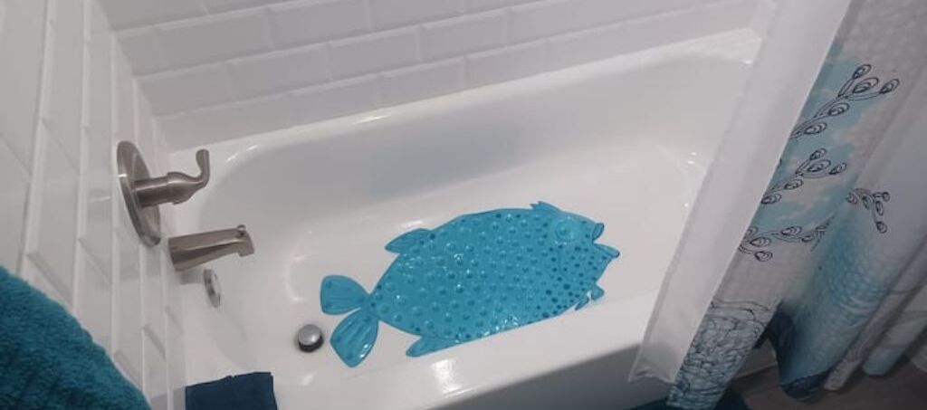 Sininen kylpyamme, jossa on sininen kylpymatto ja paisley-kuvioitu suihkuverho.
