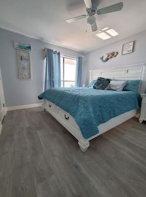 A bedroom with a bed, a ceiling fan, and a window with curtains. - Come and Enjoy Galvestons Gem 💎  (Galveston)