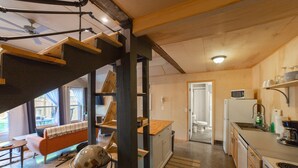 Une cuisine moderne avec un escalier en bois, un coin repas avec un canapé et une vue sur l’extérieur.