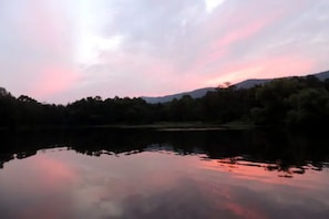 Un lago tranquilo que refleja un cielo al atardecer con árboles al fondo.