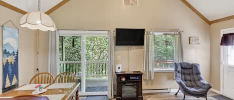 A spacious living area with a dining table, chairs, a television, and a comfortable armchair.