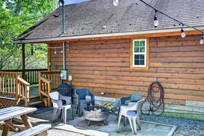 Eine Holzhütte mit einer Terrasse, Sitzgelegenheiten im Freien, einer Feuerstelle und Lichterketten.