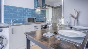 Cocina moderna con salpicadero de azulejos azules, un microondas, una copa de vino y una botella sobre la encimera.