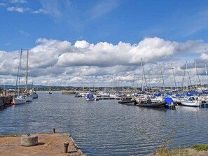 En lystbådehavn med flere både i havnen, stille vand og en klar himmel.
