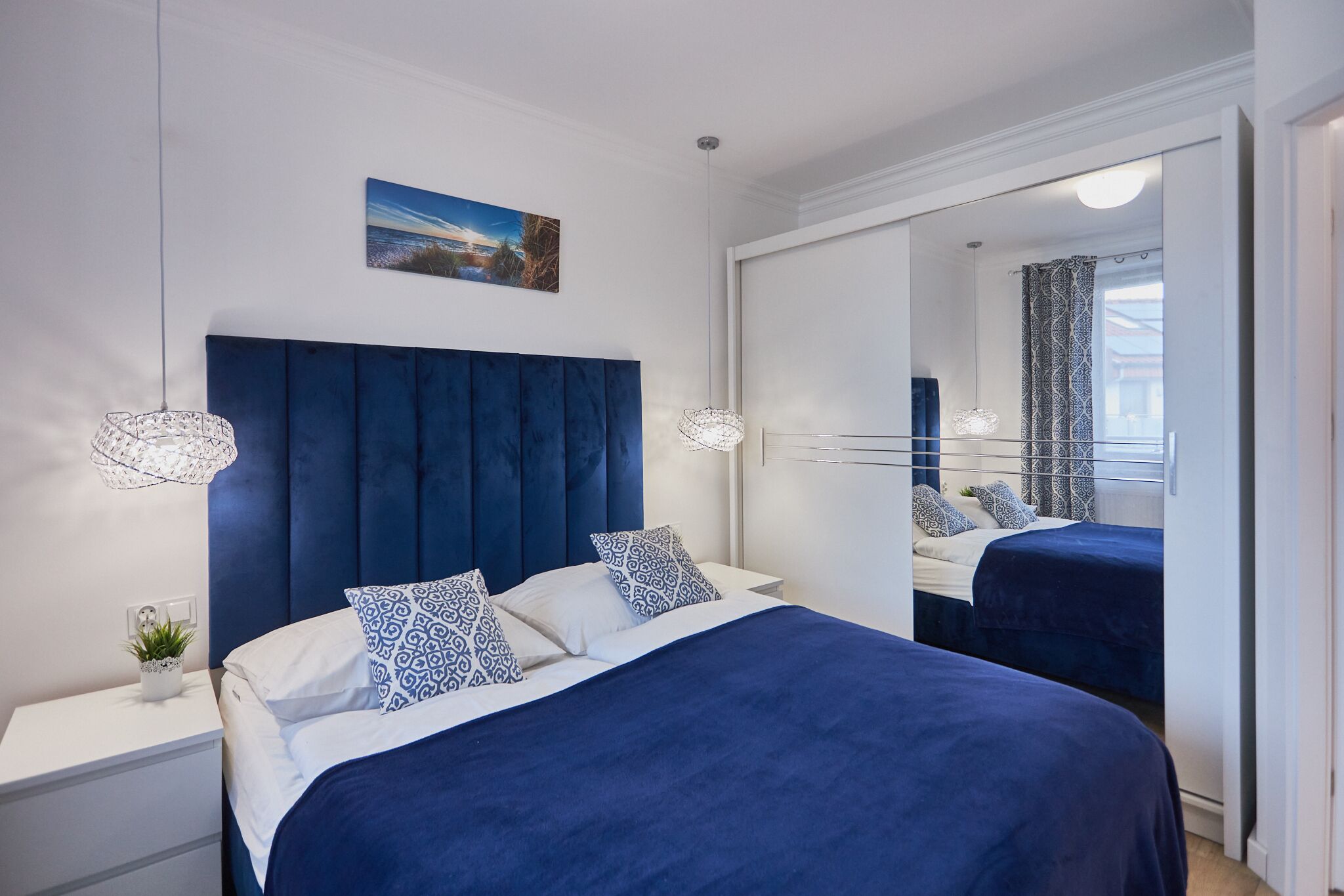 Una camera da letto moderna con un letto grande, un comodino, uno specchio e vista all'esterno.