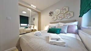 A neatly arranged bedroom with a large bed, a bedside table, and a mirror. - Apartamenty Swinoujscie K Rozy Wiatrow 2 (Swinoujscie)