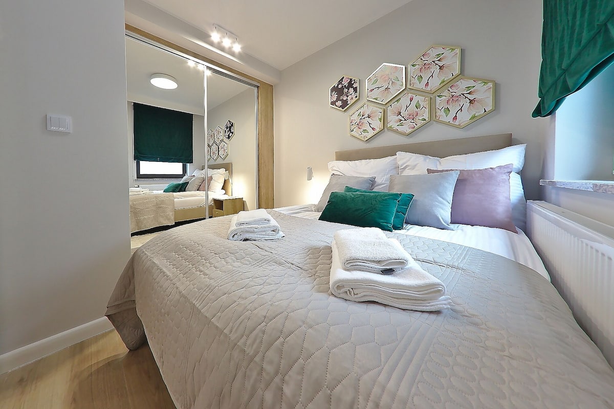 A neatly arranged bedroom with a large bed, a bedside table, and a mirror.