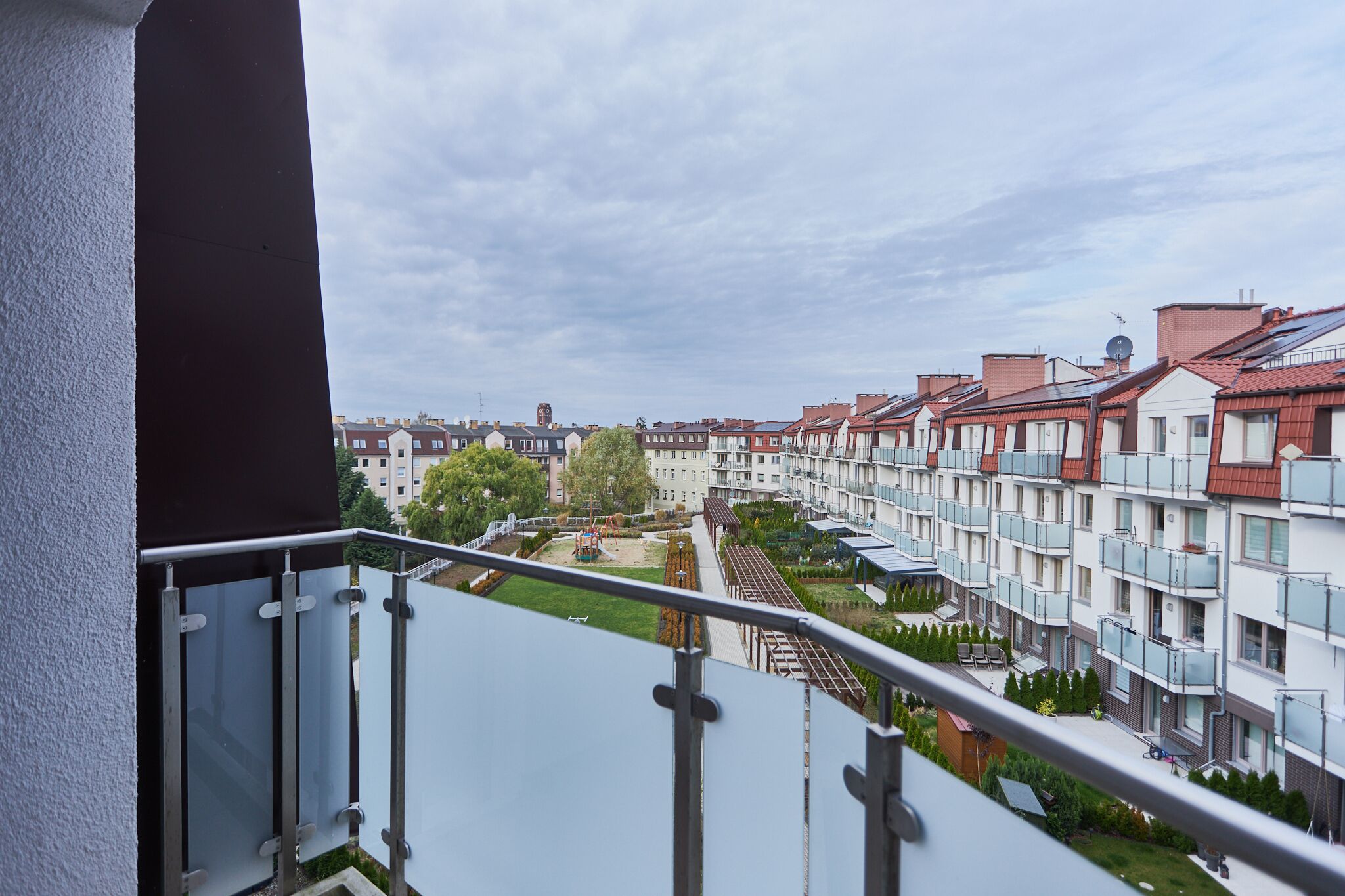 Zona residencial con edificios de apartamentos modernos, cielo despejado y un jardín visible.