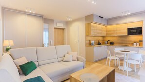 A modern living room with a sofa, coffee table, and a dining area with chairs. - Apartamenty Swinoujscie K Rozy Wiatrow 2 (Swinoujscie)