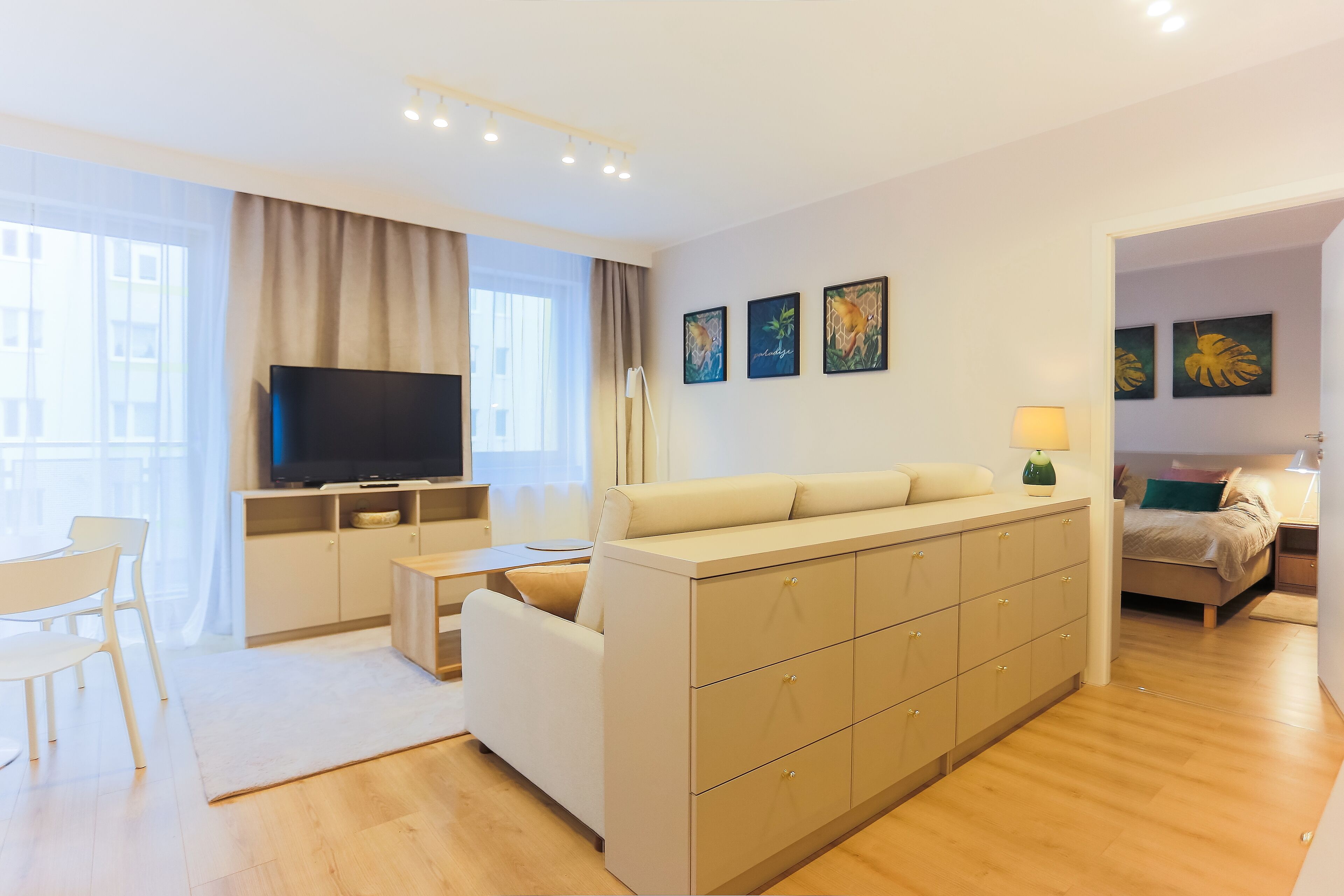 A modern living room with a sofa, TV, and artwork on the wall.