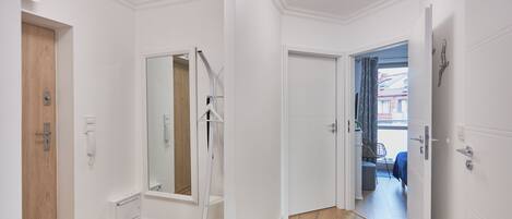 A modern, well-lit hallway with a wooden door, a mirror, and a black mat on the floor.