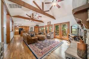 A spacious living area with wooden beams, a large rug, and a fireplace. - Cozy Cottage on 140 Acres | Just 30 minutes from Tulsa (Haskell)