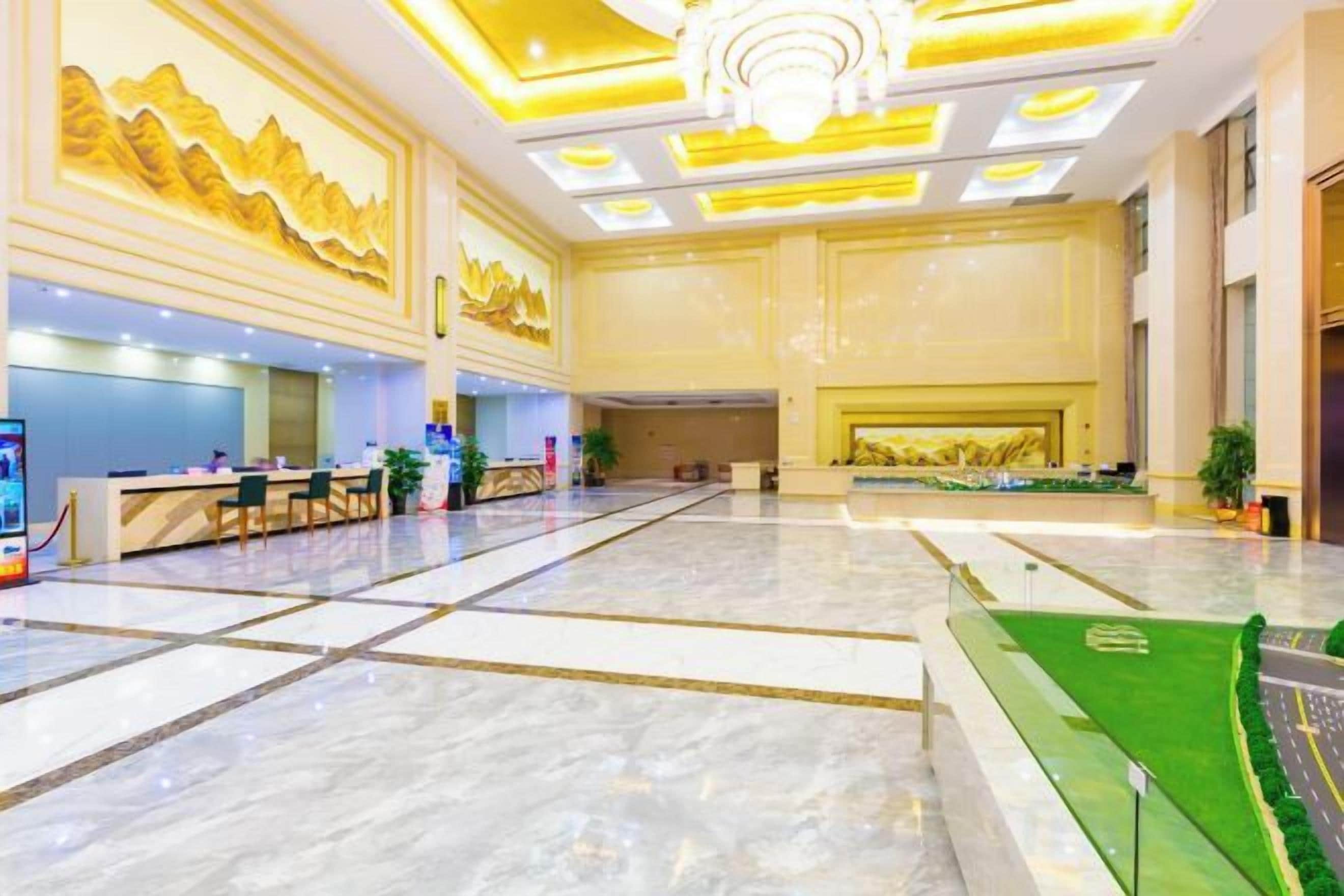 A spacious lobby with a reception desk, seating area, and a green artificial turf feature.