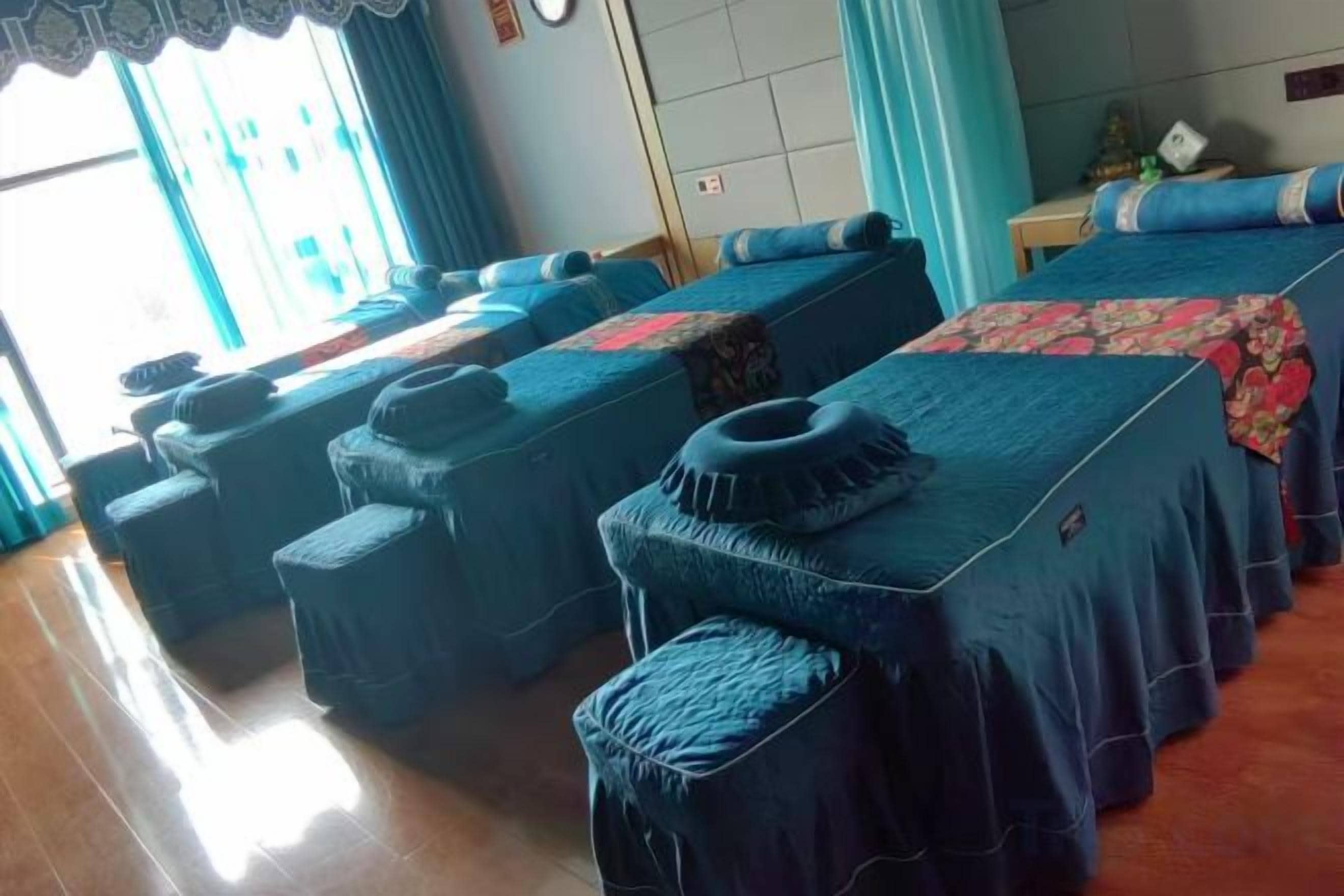A hotel room with a long bed, a smaller bed, and a sofa bed. There are two side tables with lamps.