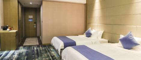 Una habitación de hotel con dos camas, una mesita de noche, un cabecero y una alfombra estampada.