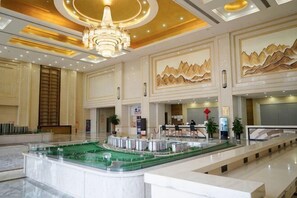 A spacious lobby with a central island, a chandelier, and a reception desk.