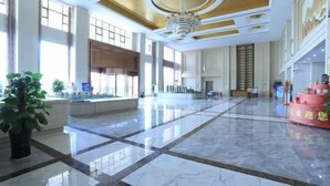 A spacious lobby with a marble floor, large windows, and a chandelier.