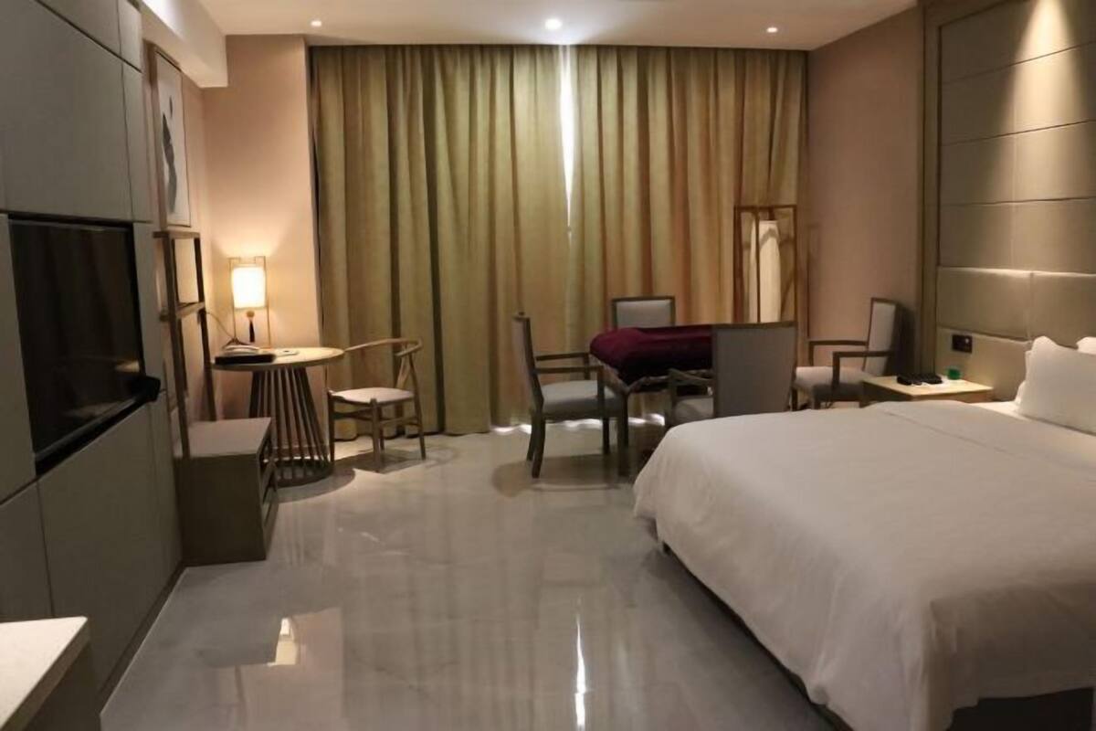 A hotel room with a bed, desk, chair, and a TV.