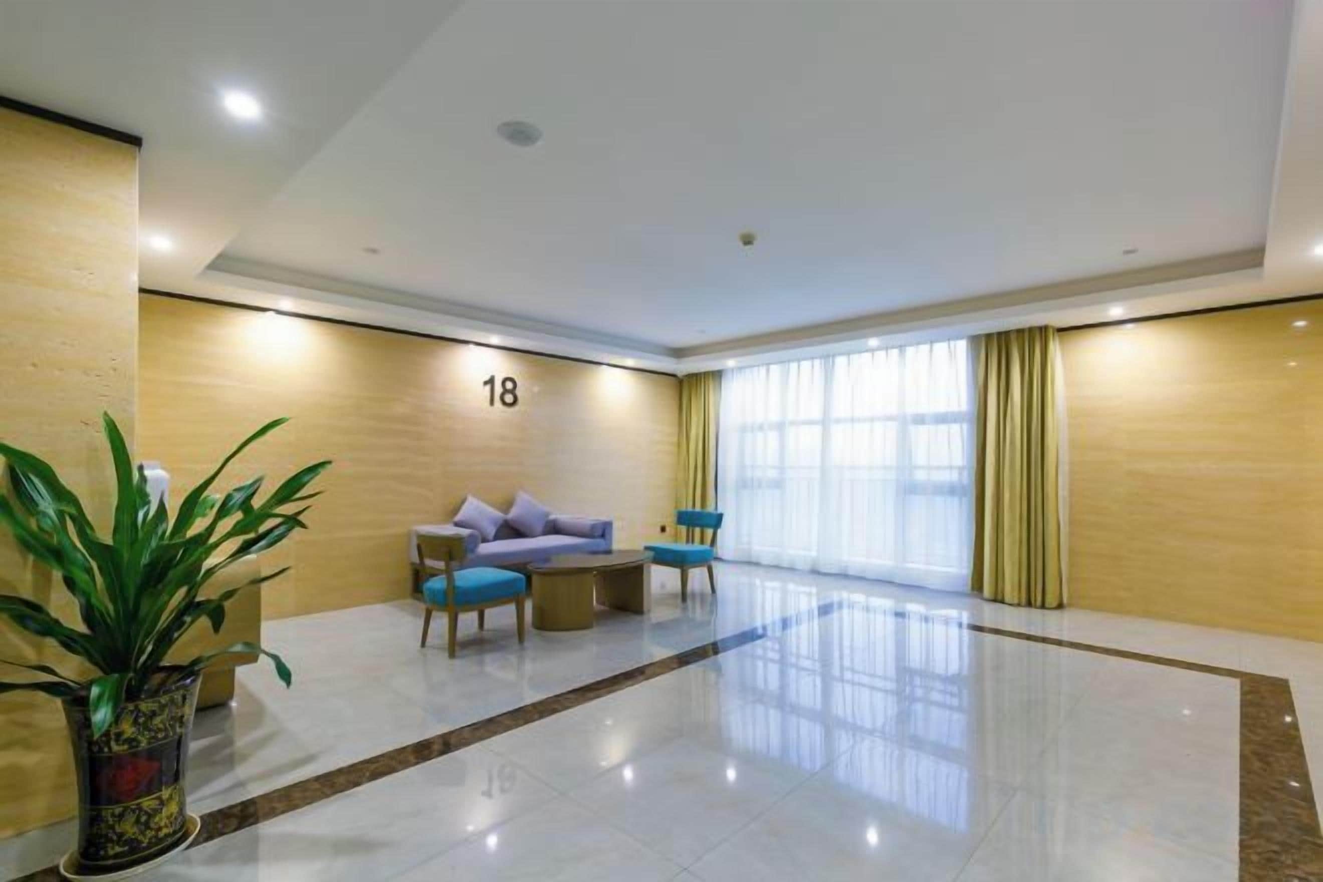 A hotel lobby with a reception desk, seating area, and a large window.