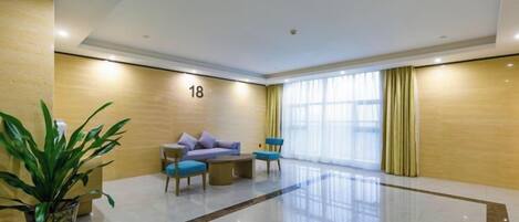 A hotel lobby with a reception desk, seating area, and a large window.