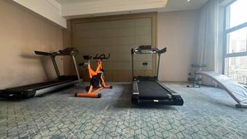A hotel room with a treadmill, stationary bike, and elliptical machine.