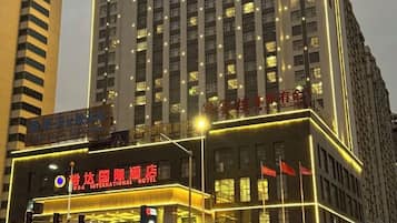 A hotel with a prominent sign, multiple floors, and illuminated windows.