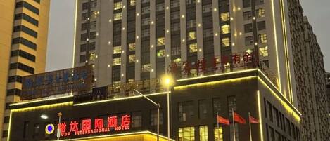 Un hotel con un cartel llamativo, varios pisos y ventanas iluminadas.