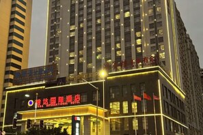 A hotel with a prominent sign, multiple floors, and illuminated windows. - Yuda International Hotel (Wuxuan)