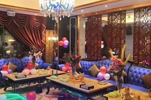 A room with a blue sofa, a chandelier, and a decorative wall.