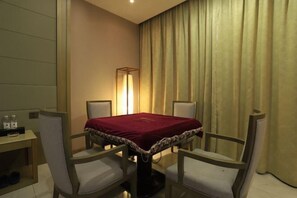 A hotel room with a table set for two, a lamp, and a curtain.
