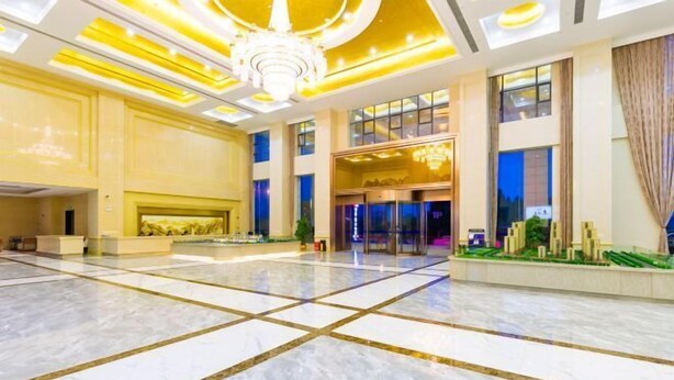 A spacious lobby with a marble floor, a chandelier, and a reception area.