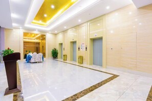 A spacious hotel lobby with a marble floor, a podium, and a seating area with chairs. - Yuda International Hotel (Wuxuan)