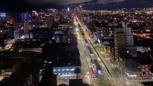 A nighttime cityscape with illuminated buildings and a busy street.