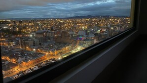 A nighttime cityscape viewed from a window, featuring a densely packed urban area with illuminated buildings and streets.