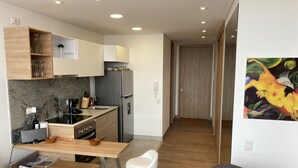 A modern kitchen with a built-in oven, a refrigerator, and a dining area with a table and chairs.