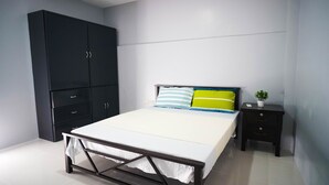A bedroom with a bed, a wardrobe, a bedside table, and a small potted plant. - Cozy and homelike accommodations (Olongapo City)