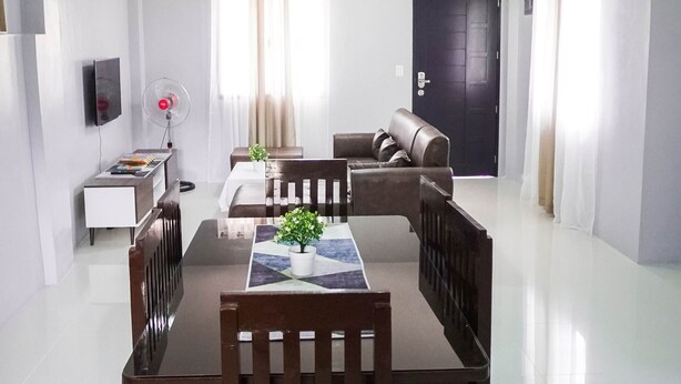 A dining area with a table and chairs, a sofa, a small side table, and a fan. - Cozy and homelike accommodations (Olongapo City)
