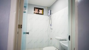 A bathroom with white marble tiles, a shower with a handheld showerhead, and a toilet. - Cozy and homelike accommodations (Olongapo City)