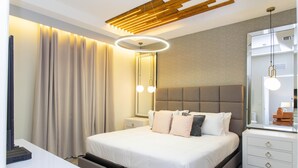 Moderni hotellihuone, jossa on suuri sänky, yöpöydät, peili ja kattovalaisin.