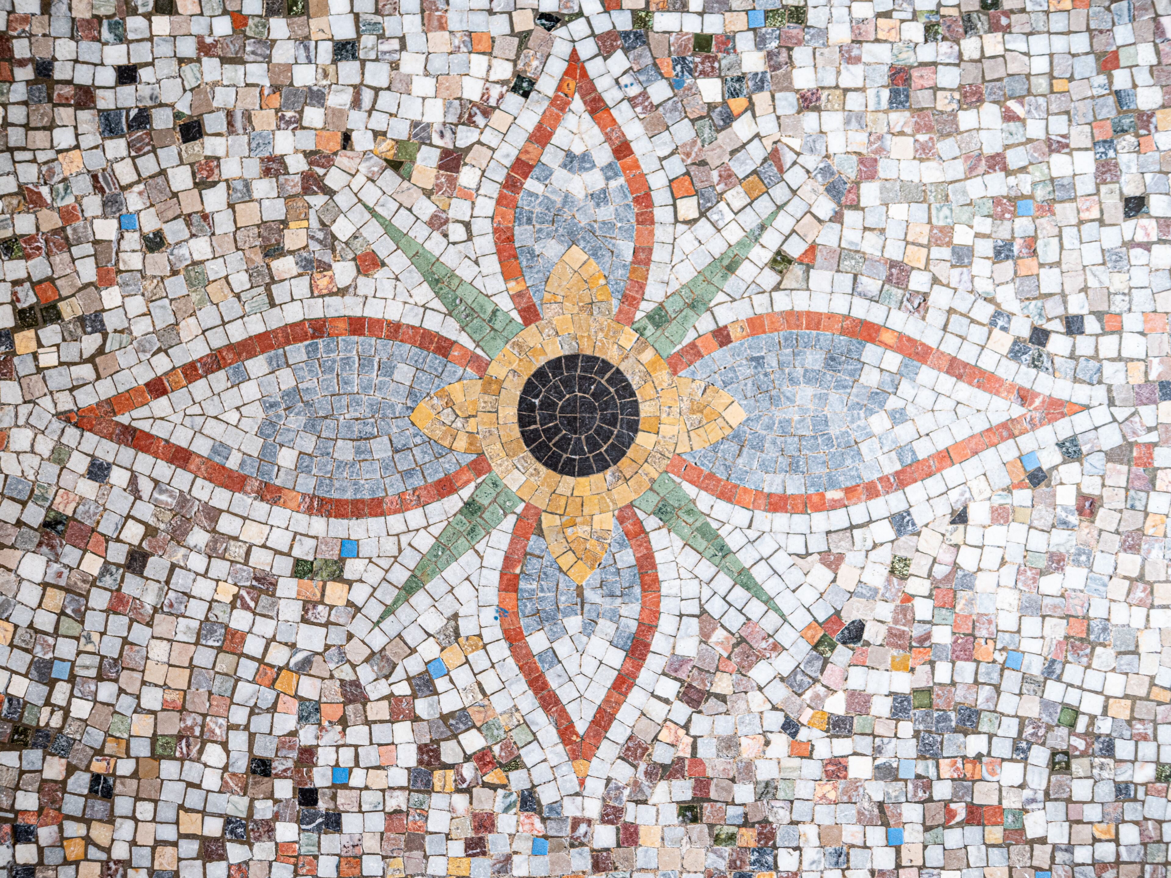 Un detallado suelo de mosaico con un diseño circular central rodeado de motivos radiantes.