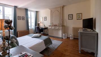 A bedroom with a bed, desk, chair, and a television.
