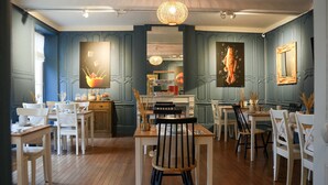 A dining area with wooden tables and chairs, a central serving station, and decorative wall art.