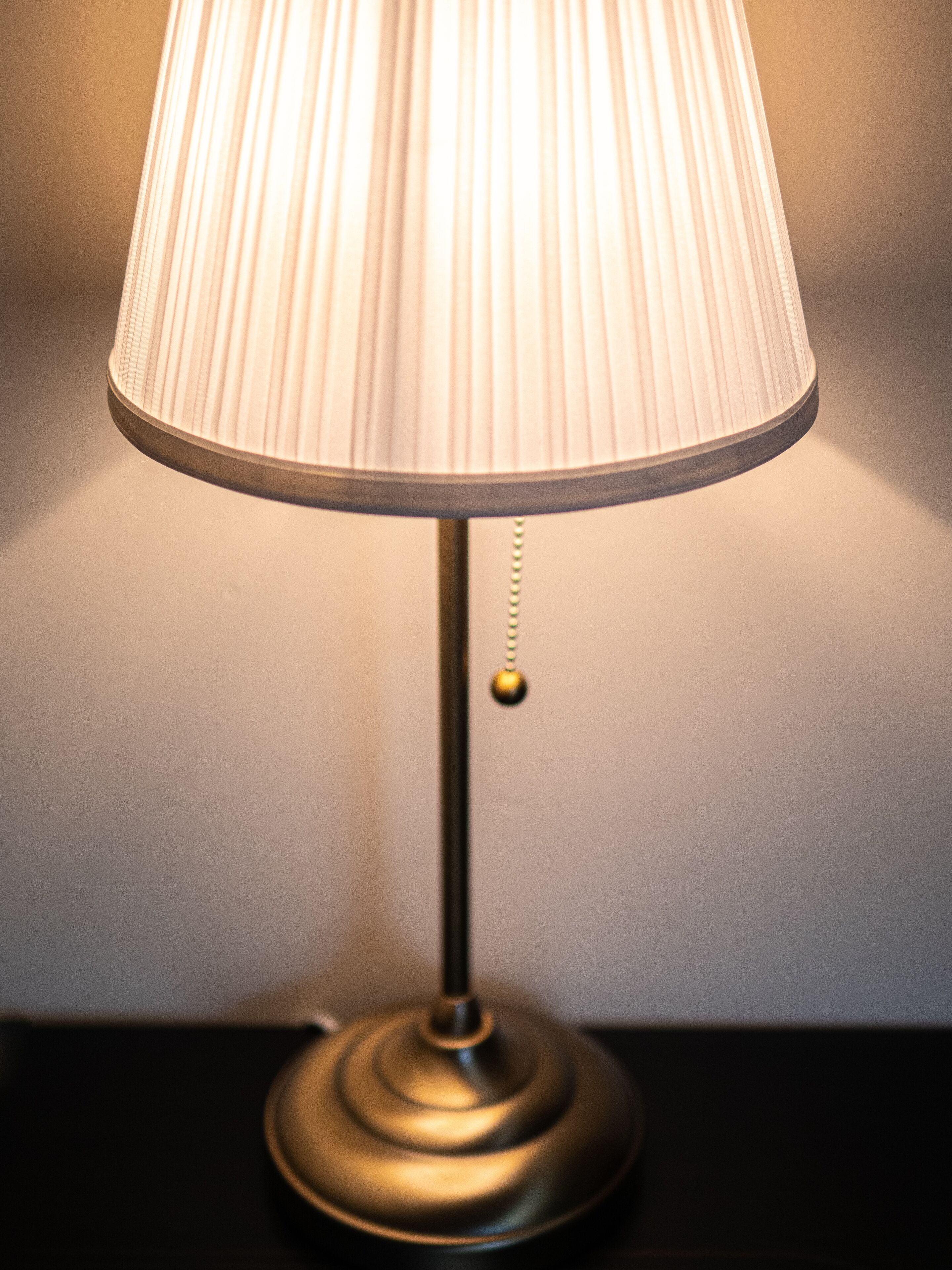 A table lamp with a pleated lampshade and a metallic base.