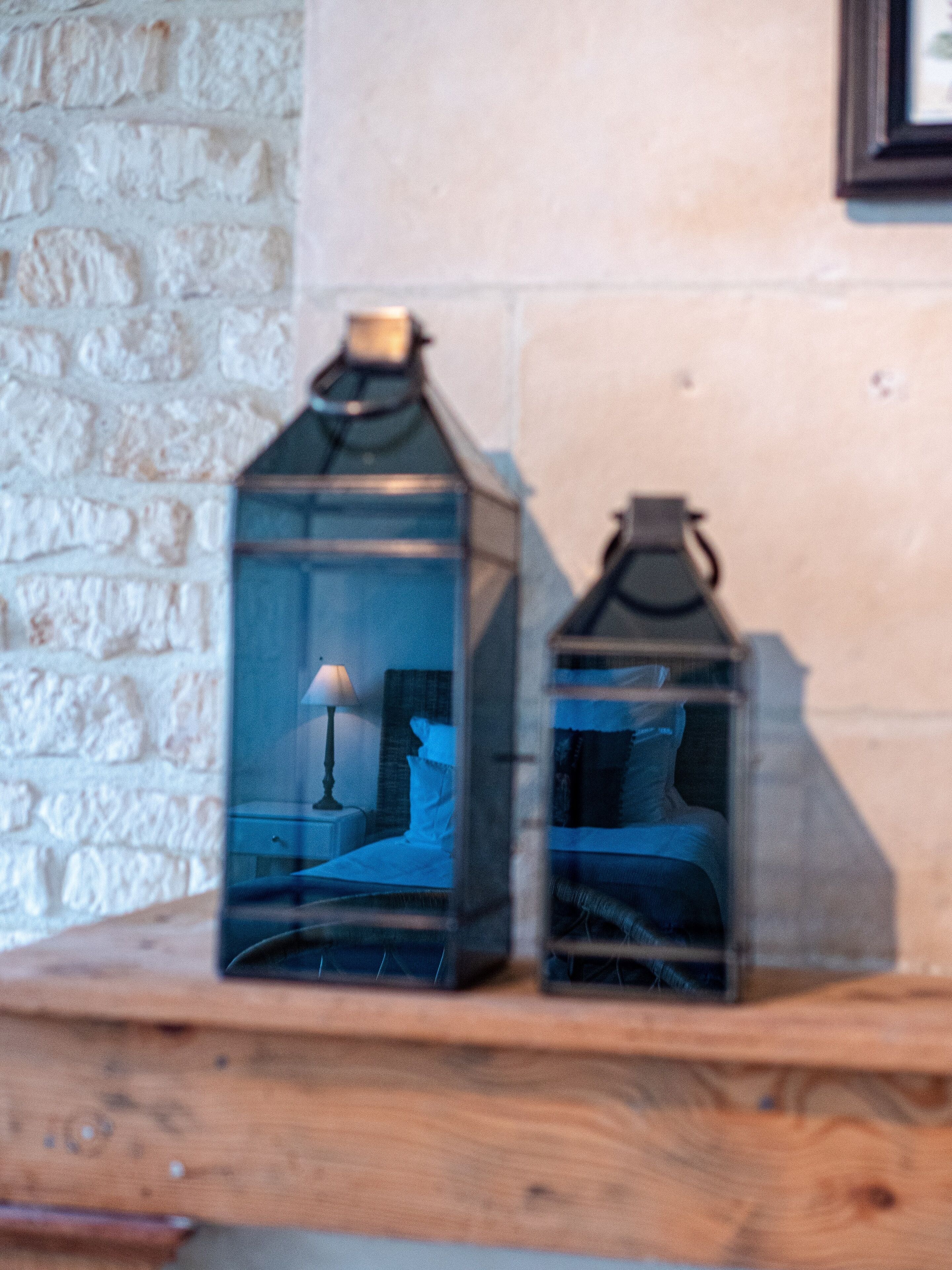 Two glass lanterns on a wooden shelf.