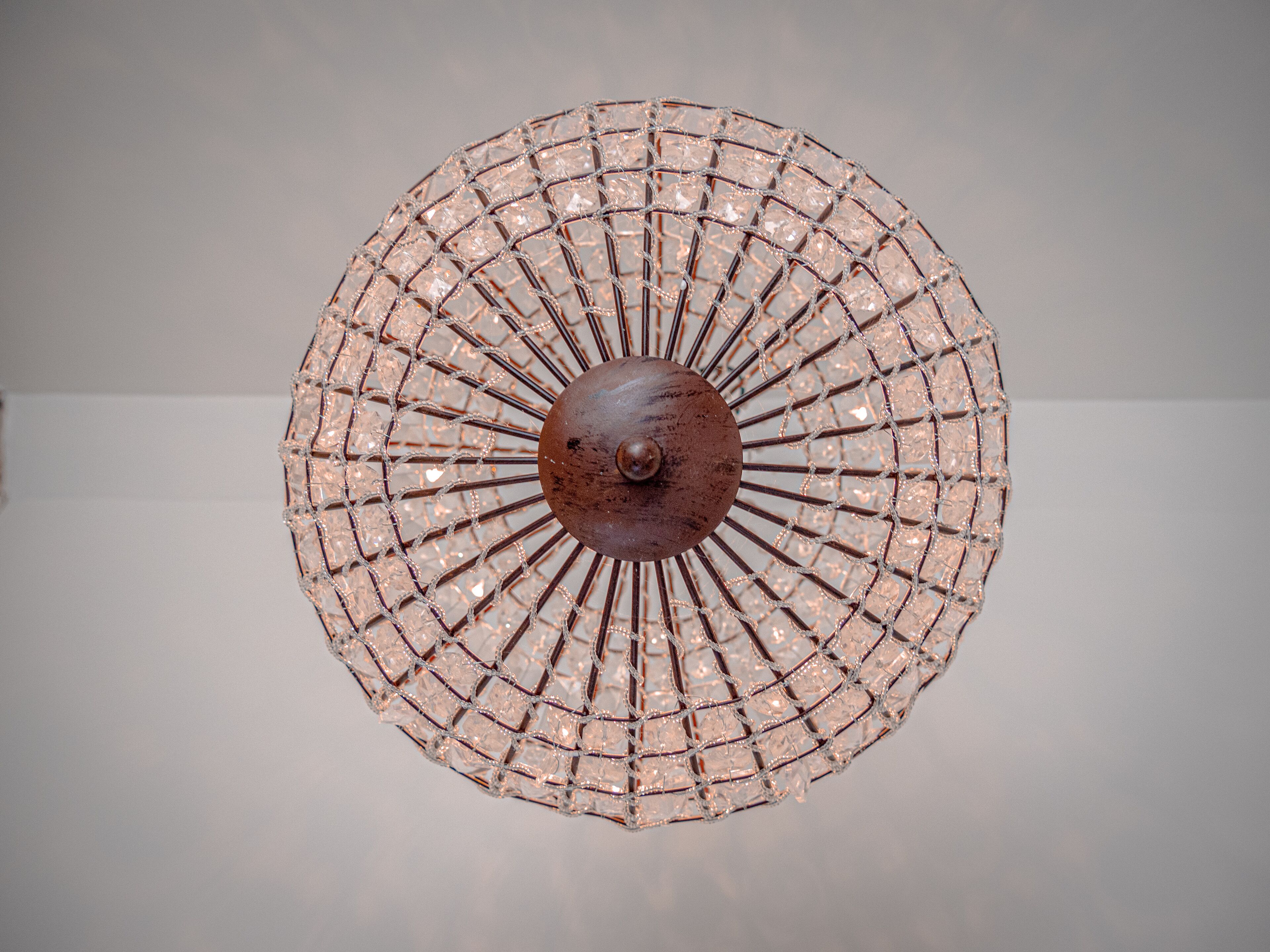 Una lámpara de araña circular con una esfera metálica central y una estructura de entramado de alambre.